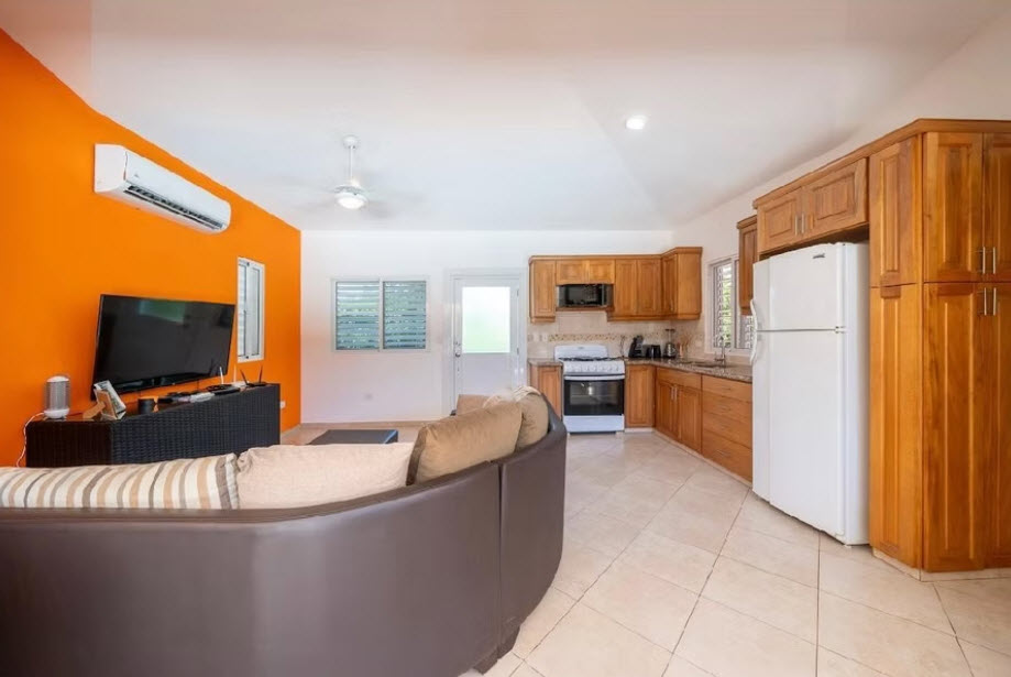 Modern open-plan living room and kitchen with orange accent wall