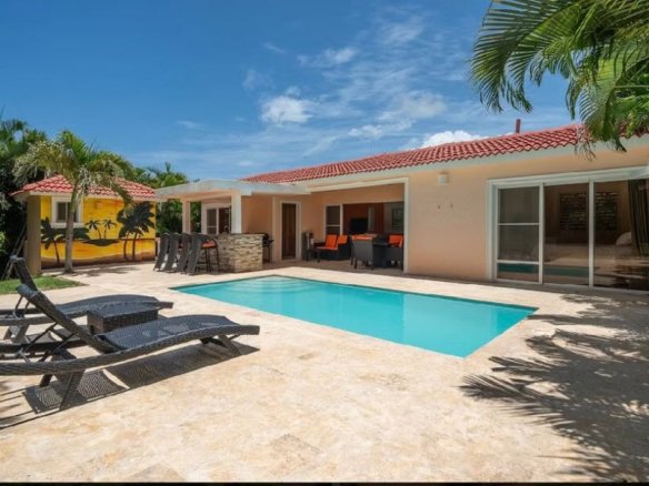 Luxury villa with pool, lounge chairs, and tropical mural