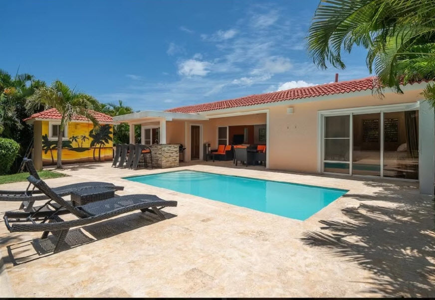 Luxury villa with pool, lounge chairs, and tropical mural