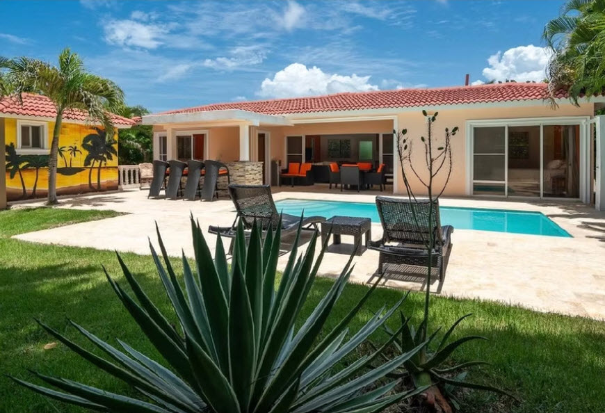 Luxury villa with pool, lounge chairs, and tropical mural