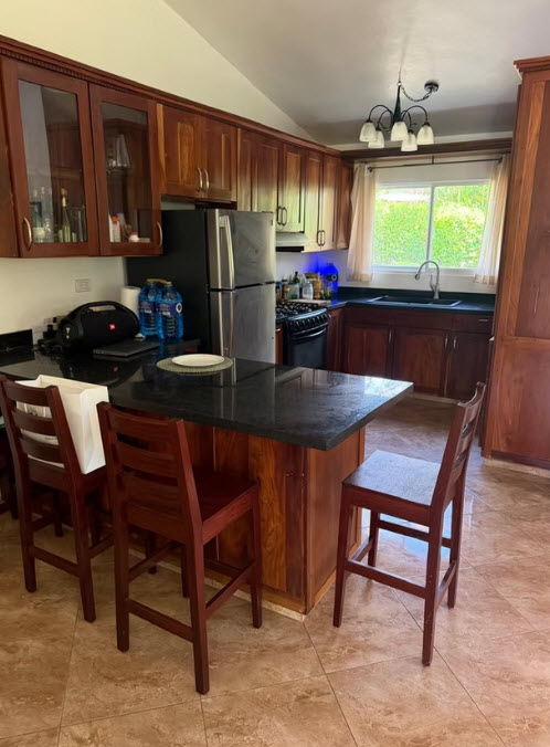 Modern kitchen with dark granite island, stainless steel appliances, and wooden cabinets.