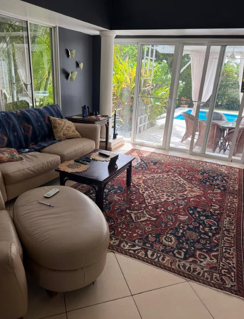 Living room with ornate rug, cream sofa, and pool view