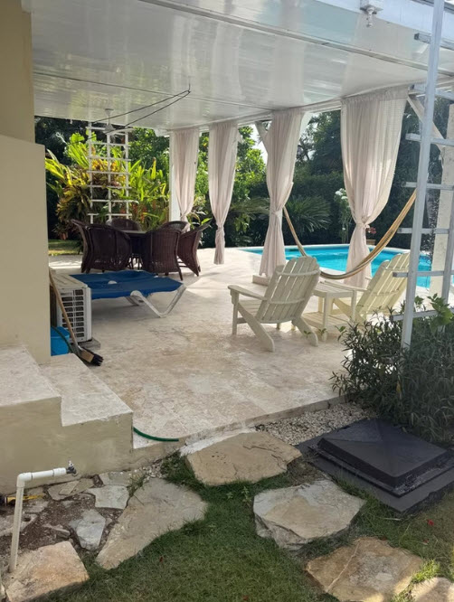 Covered patio with lounge chairs, dining set, and pool beyond