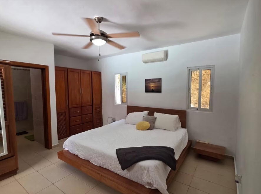 Spacious bedroom with king-size bed, wooden wardrobe, and ceiling fan.