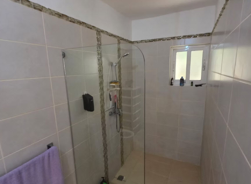 Modern tiled bathroom with a glass-enclosed shower and small window