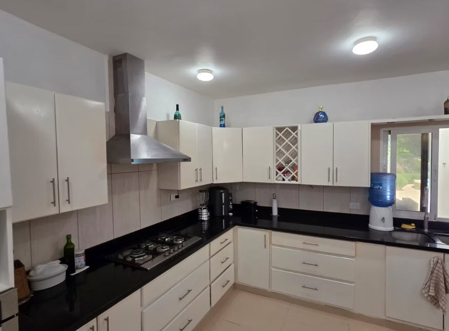 Modern white kitchen with stainless steel appliances and black countertops