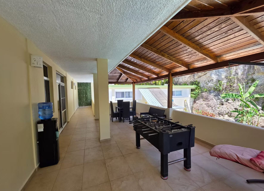 Covered patio with foosball table, seating, and water cooler