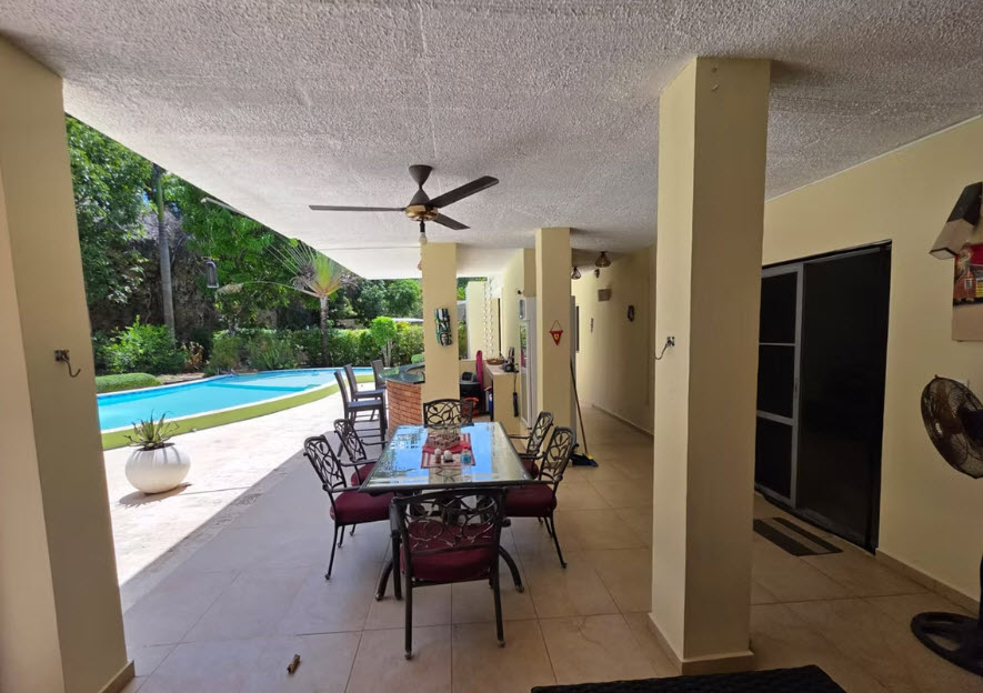 Outdoor patio dining area with pool view and ceiling fan