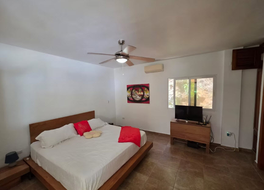 Spacious bedroom with king-size bed, ceiling fan, and TV