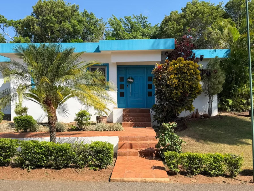 Modern tropical home with bright blue door and lush landscaping