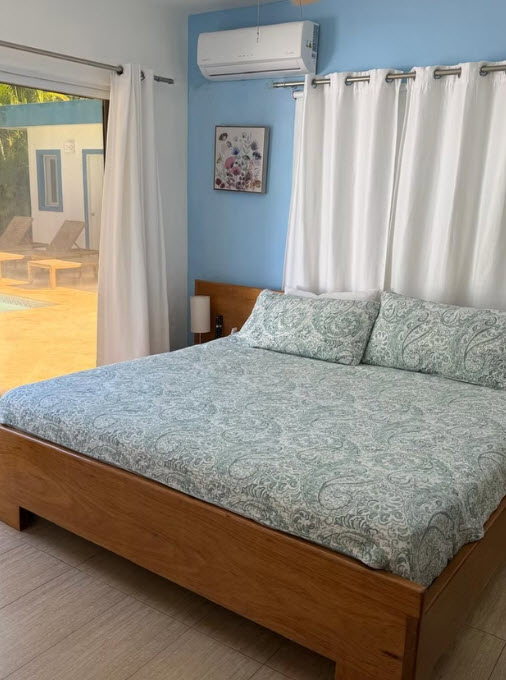 Bedroom with a king-size bed, patterned bedding, and pool view
