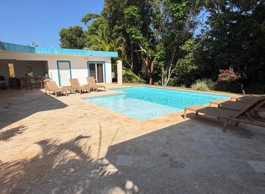 Luxury villa with pool and lounge chairs in tropical setting