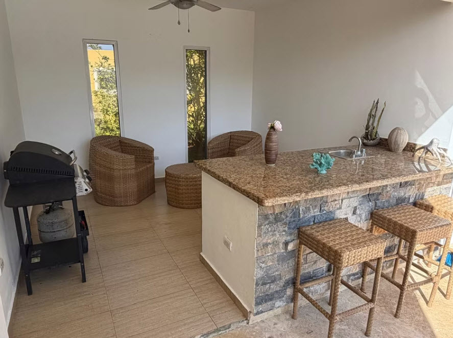 Outdoor kitchen with granite bar, seating, and grill