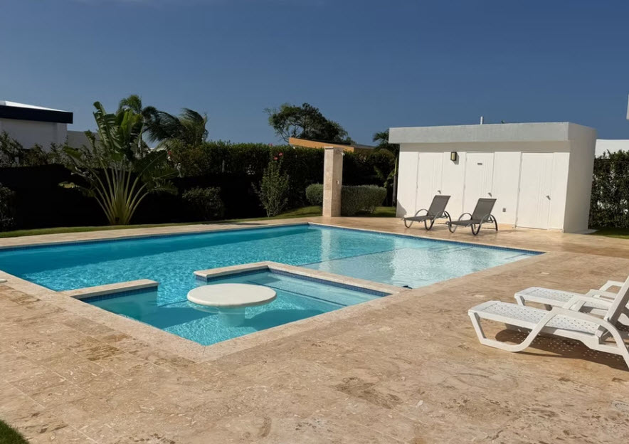 Luxury swimming pool with swim-up bar and lounge chairs in a tropical setting.