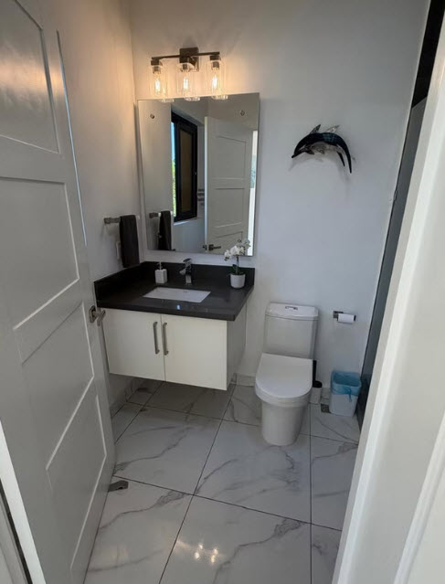 Modern bathroom with marble tile floor, floating vanity, and wall art.