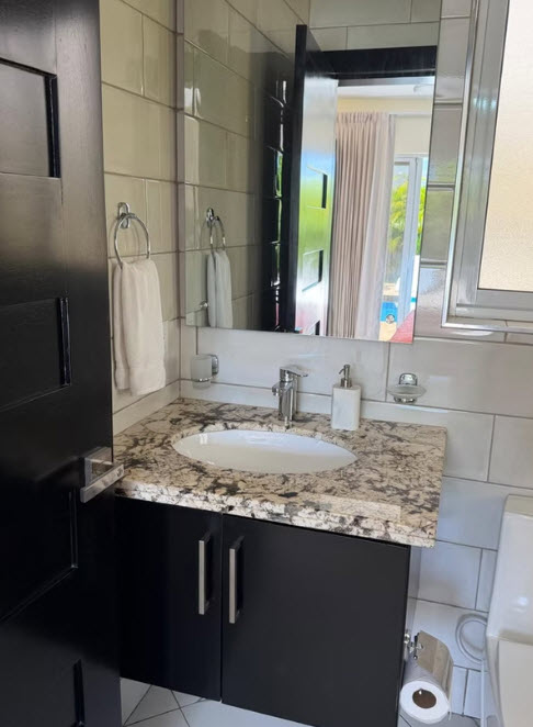 Modern bathroom vanity with granite countertop, black cabinets, and white subway tile