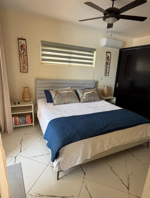 Modern bedroom with queen bed, blue accent blanket, and ceiling fan
