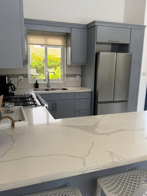 Modern gray kitchen with white quartz countertops and stainless steel appliances.