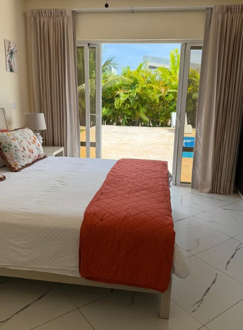 Bedroom with a view of a tropical garden and swimming pool