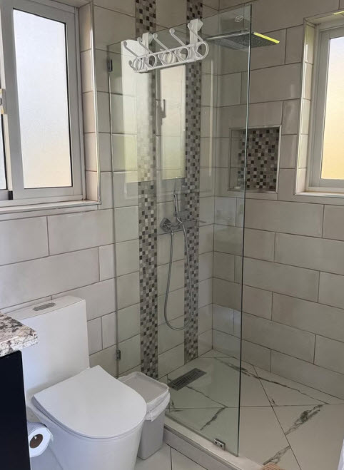 Modern bathroom with glass shower enclosure, white toilet, and tiled walls
