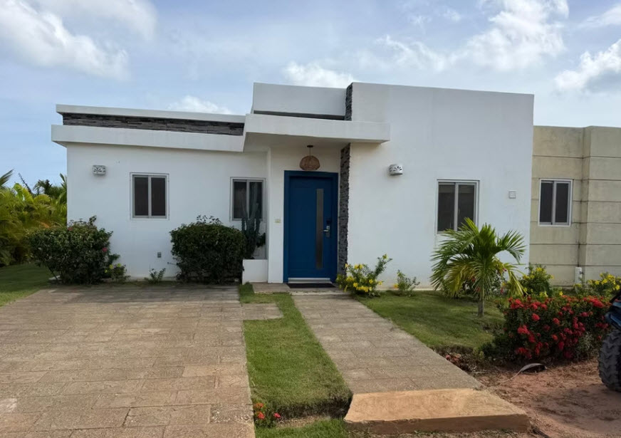 Modern white house with blue door and landscaped yard