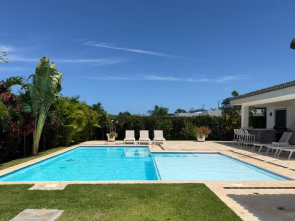 Luxury villa with a large swimming pool and lounge chairs in a tropical setting