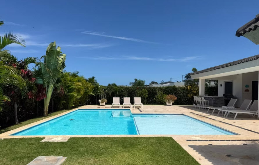Luxury villa with a large swimming pool and lounge chairs in a tropical setting
