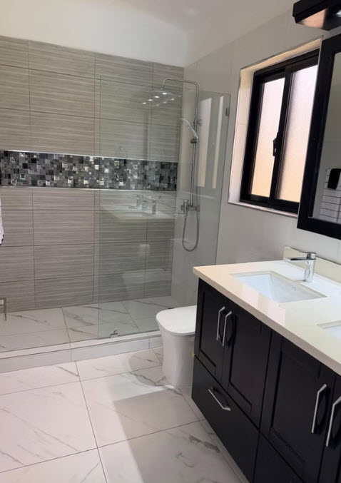 Modern bathroom with double vanity, glass shower, and tiled walls