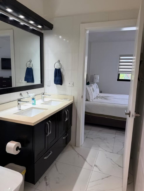 Modern bathroom with double vanity and view of bedroom