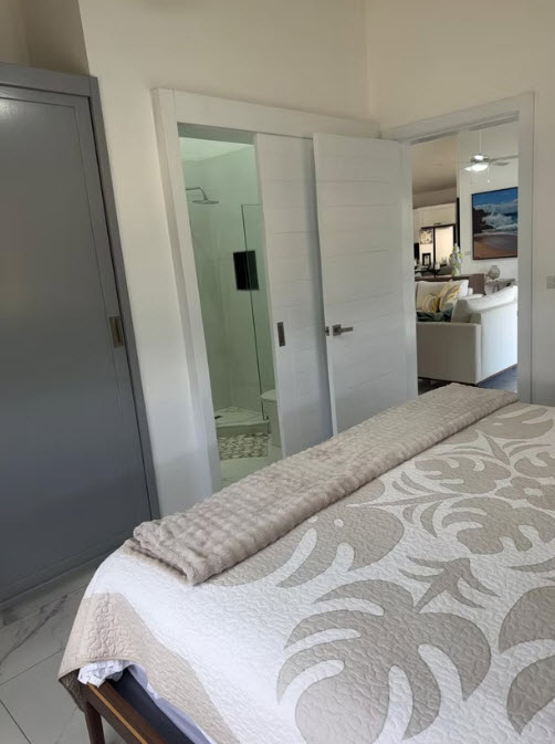 Modern bedroom with sliding doors open to a spa-like bathroom and living area