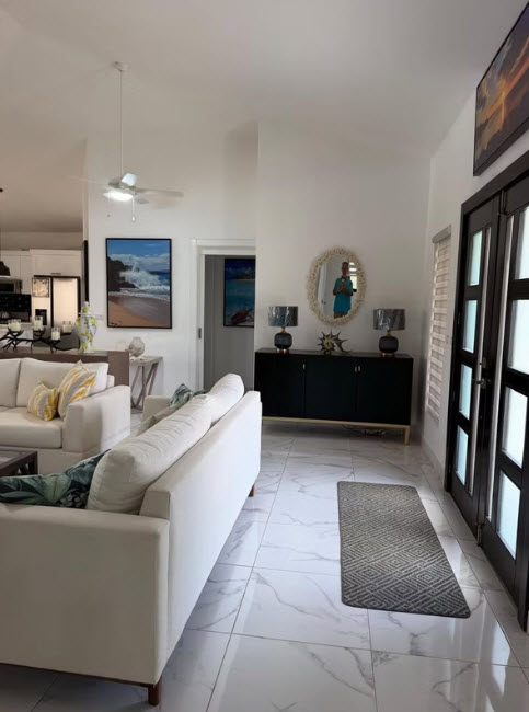 Modern living room with white sofas, a dark sideboard, and beach-themed art