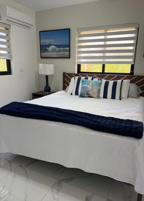 Coastal bedroom with white bedding, navy accents, and ocean artwork