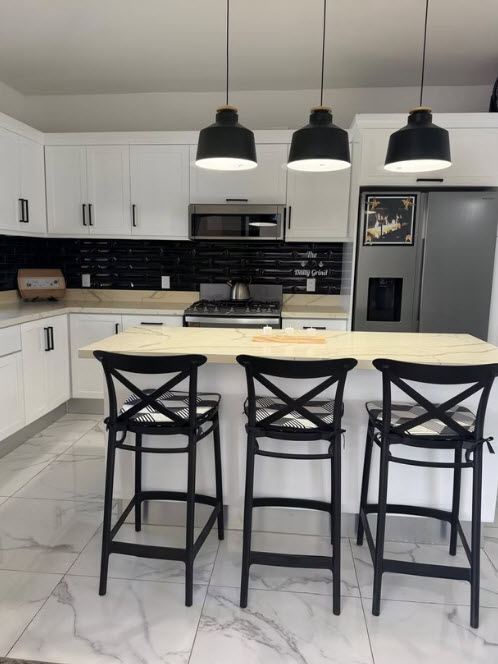 Modern white kitchen with island, bar stools, and black subway tile backsplash