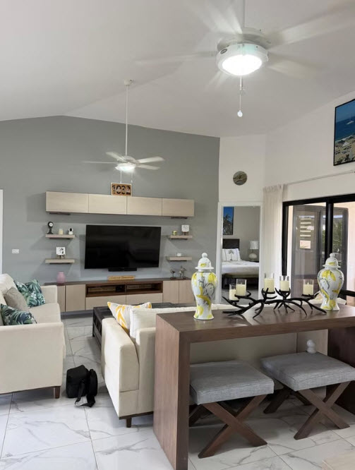 Modern living room with beige sofas, large TV, and decorative vases.