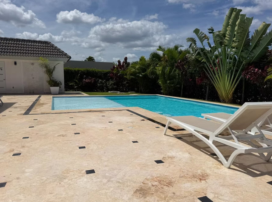 Luxury villa with a private swimming pool and lounge chairs in a tropical setting.