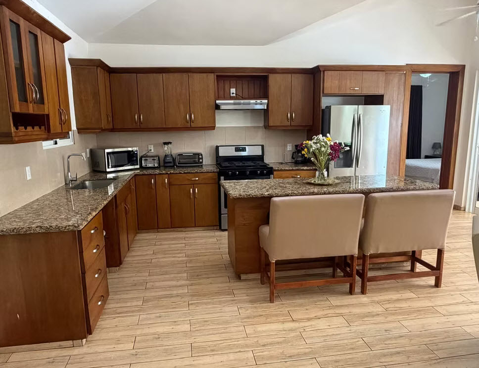 Spacious modern kitchen with wooden cabinets, granite countertops, and an island with seating.