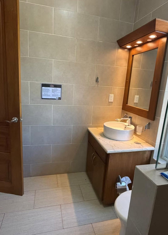 Modern bathroom with a vessel sink, wooden vanity, and tiled walls.