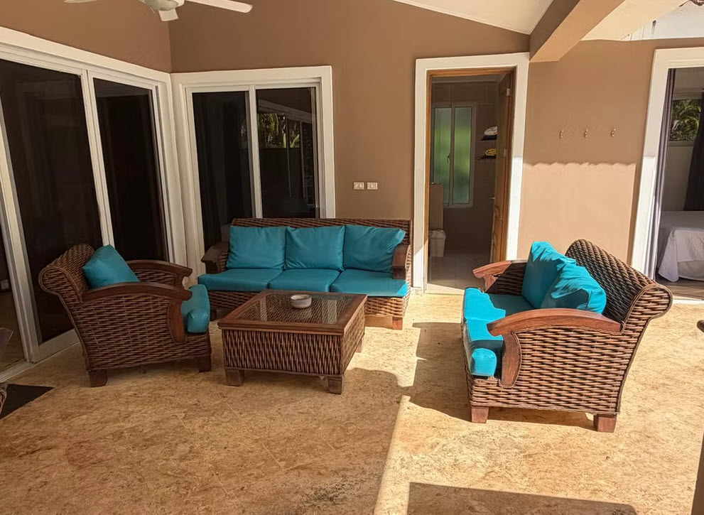 Wicker patio furniture with blue cushions on a tiled terrace