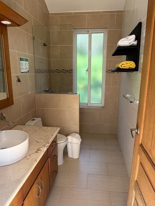 Modern bathroom with beige tiles, white sink, toilet, and glass shower