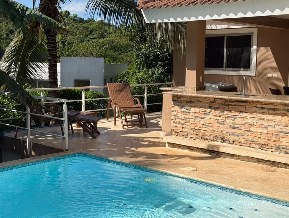 Luxury villa with pool, outdoor bar, and lounge chairs in a tropical setting