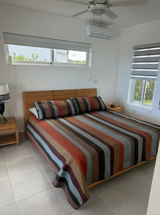 Modern bedroom with a king-size bed, colorful striped bedding, and large windows.