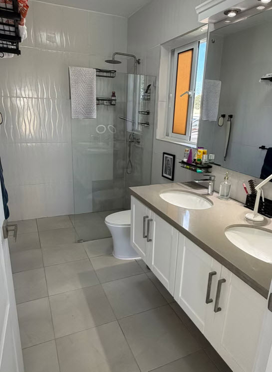 Modern bathroom with double vanity, glass shower, and white tiles