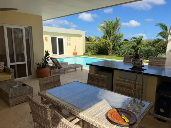 Outdoor dining area and pool at a tropical villa with an outdoor kitchen.