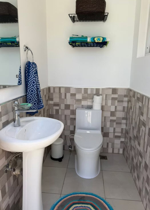 Modern bathroom with pedestal sink, toilet, and mosaic tile accents