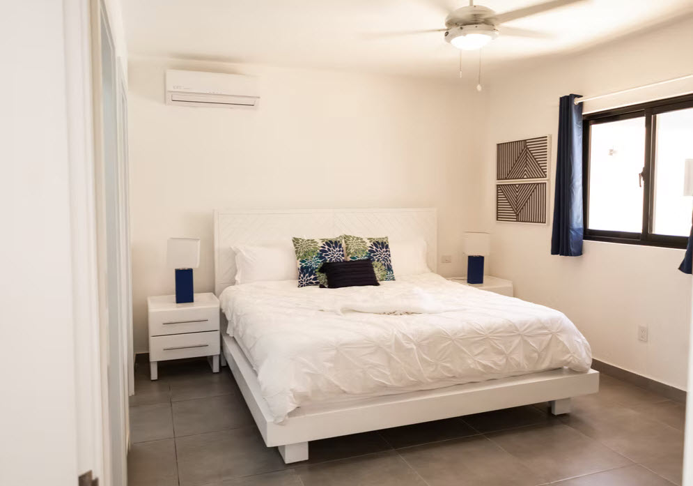Bright, modern bedroom with a king-size bed, white linens, and a ceiling fan.