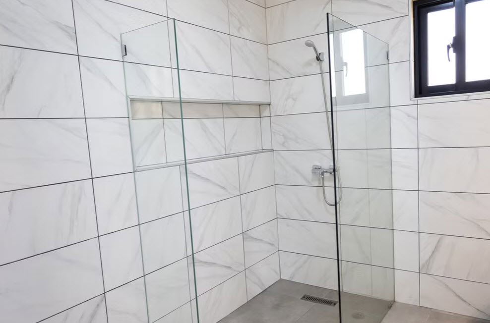 Modern walk-in shower with marble-look tiles and glass enclosure