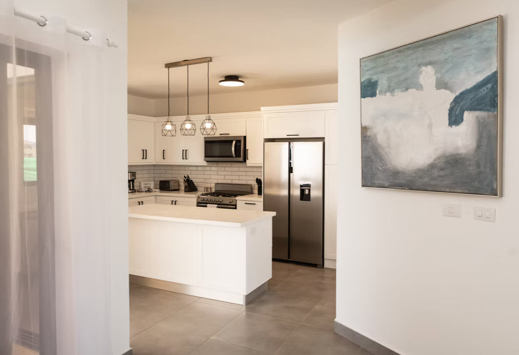 Modern white kitchen with stainless steel appliances and abstract art