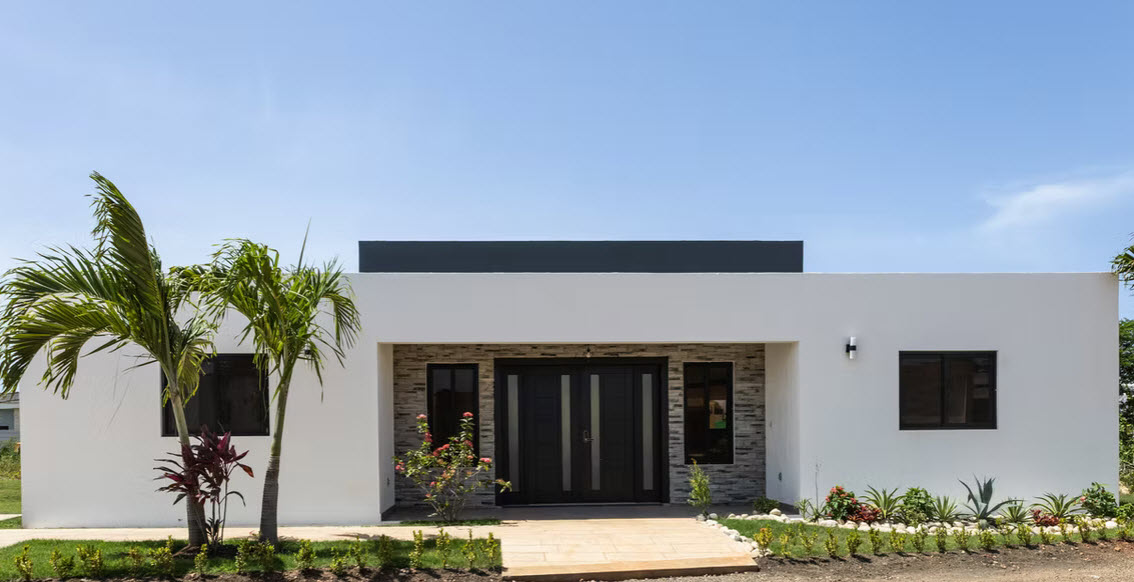 Modern white house with double doors and tropical landscaping