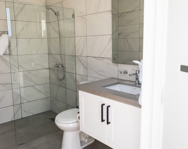 Modern bathroom with marble tiles, white vanity, and glass shower