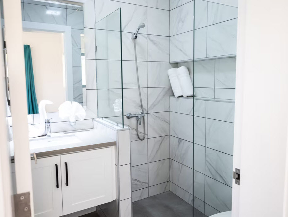 Modern bathroom with white vanity, marble tile shower, and glass enclosure